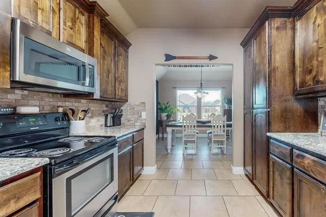 a kitchen with stainless steel appliances granite countertop a stove a sink and a microwave