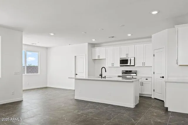 a kitchen with stainless steel appliances a sink a stove a refrigerator cabinets and a window