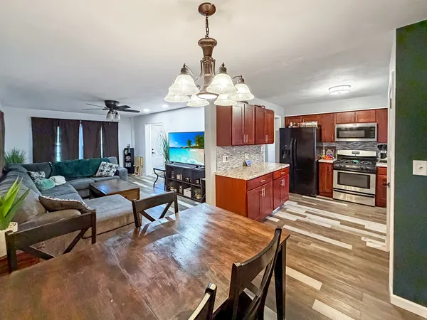 a kitchen with stainless steel appliances kitchen island granite countertop a table chairs stove and refrigerator