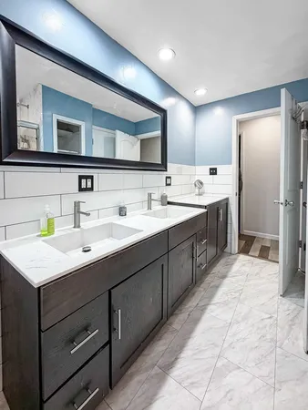a spacious bathroom with a double vanity sink toilet mirror and bathtub