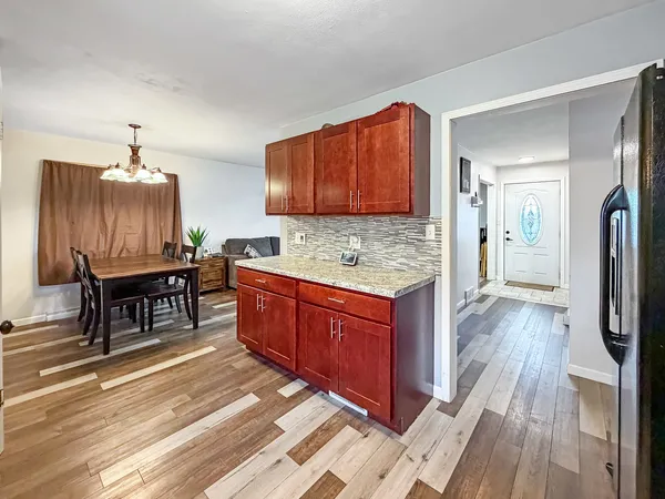 a kitchen with granite countertop a stove refrigerator and wooden floor