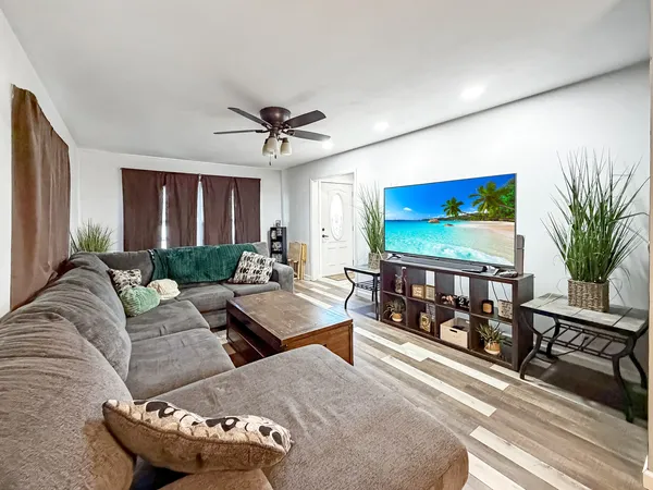 a living room with furniture a flat screen tv and a floor to ceiling window