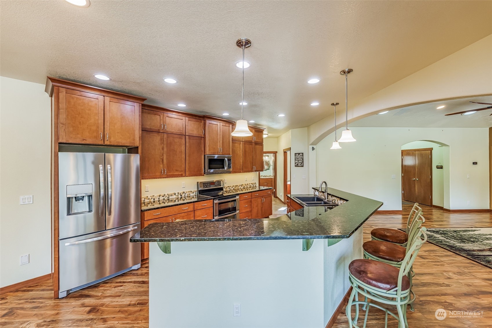 119 Marmot Loop Packwood, WA 98361 - Photo 21 of 40 a kitchen with stainless steel appliances granite countertop a refrigerator a stove a sink a dining table and chairs with wooden floor