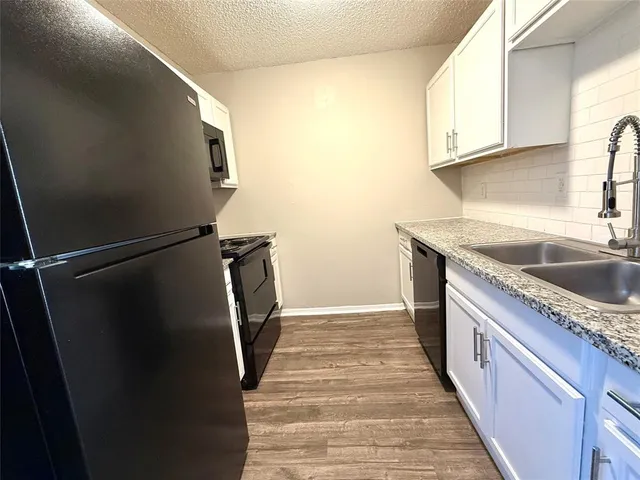 a kitchen with a sink a refrigerator and cabinets
