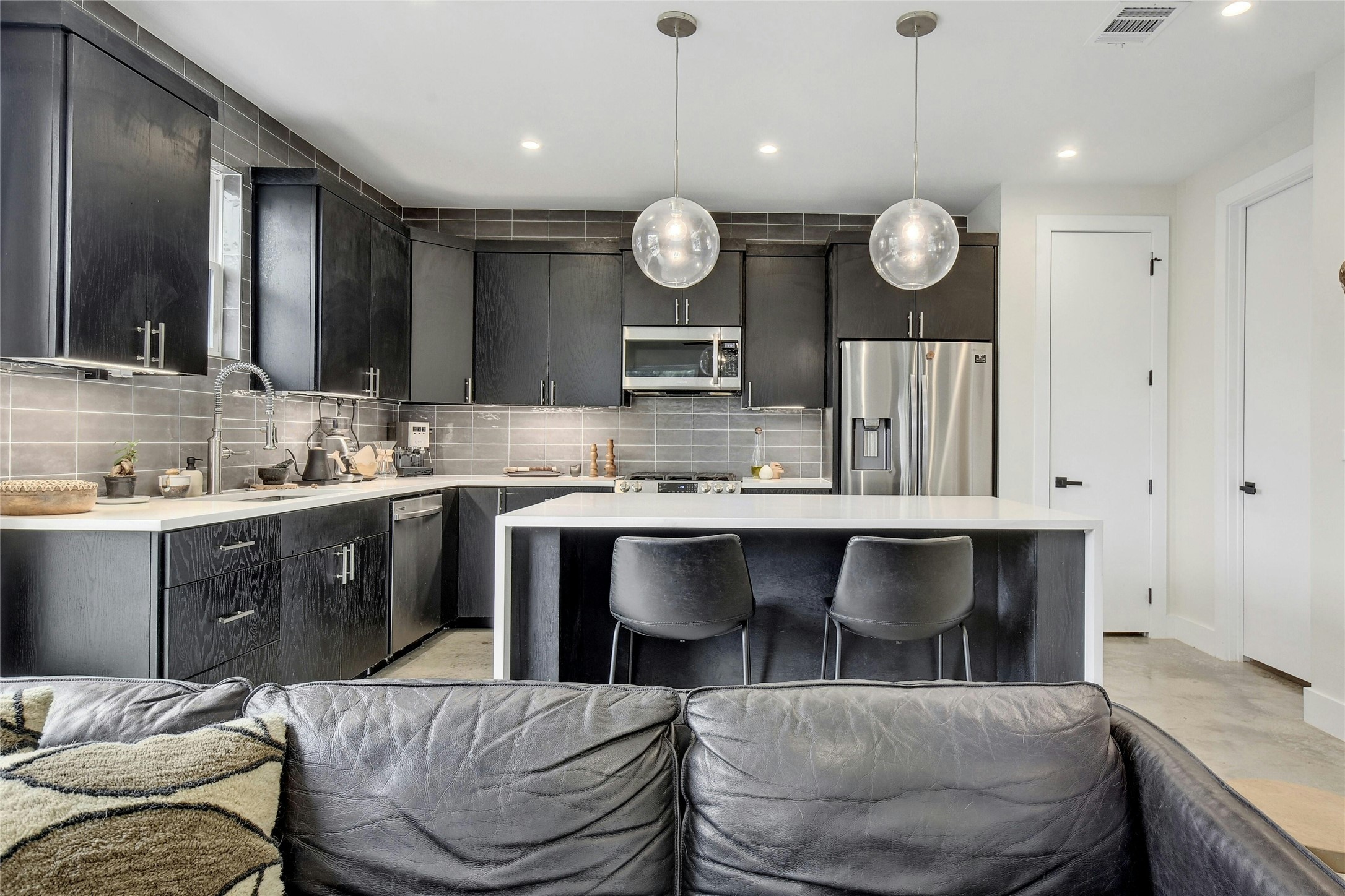 4606 Ledesma Road, Unit 2 Austin, TX 78721 - Photo 10 of 33 A contemporary kitchen space boasts sleek dark cabinetry, stainless steel appliances, and a central island with pendant lighting.