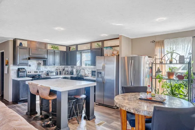 a kitchen with stainless steel appliances granite countertop a table chairs and a refrigerator