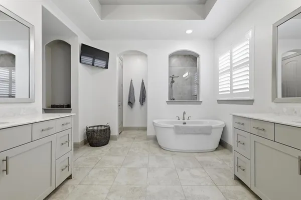 a spacious bathroom with a double vanity sink mirror and bathtub