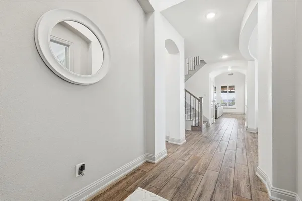 a view of a hallway with wooden floor and a bathroom