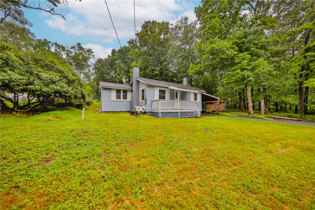 5599 Minks Pond Road Bushkill, PA 18324 - Photo 34 of 64 A charming cottage-style home nestled amongst lush greenery, featuring a welcoming front porch and expansive yard.