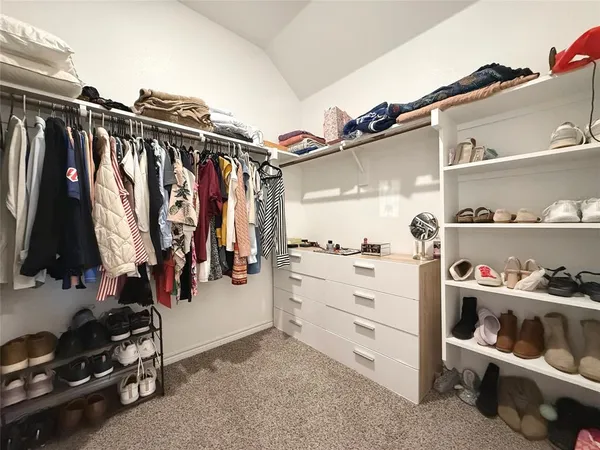 a view of walk in closet with clothes and shoes