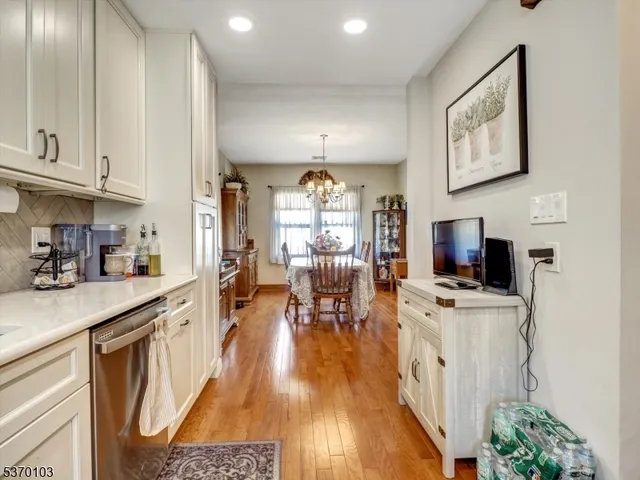 a kitchen with stainless steel appliances a stove a refrigerator a sink dishwasher and a dining table with wooden floor