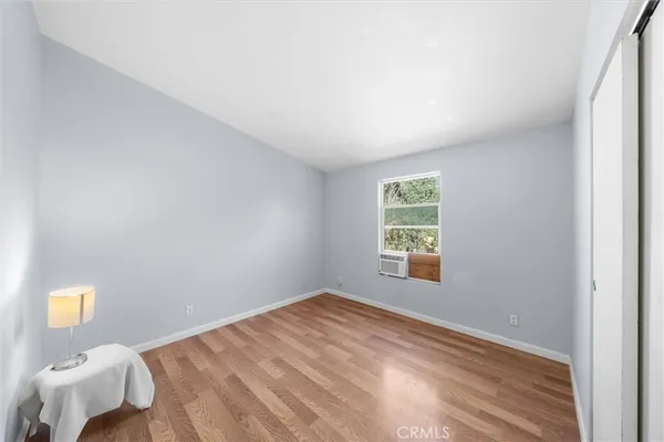 a view of a bedroom with wooden floor and window