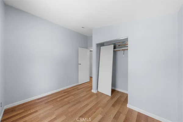a view of an empty room with wooden floor and closet