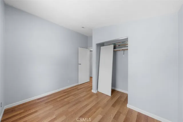 a view of an empty room with wooden floor and closet