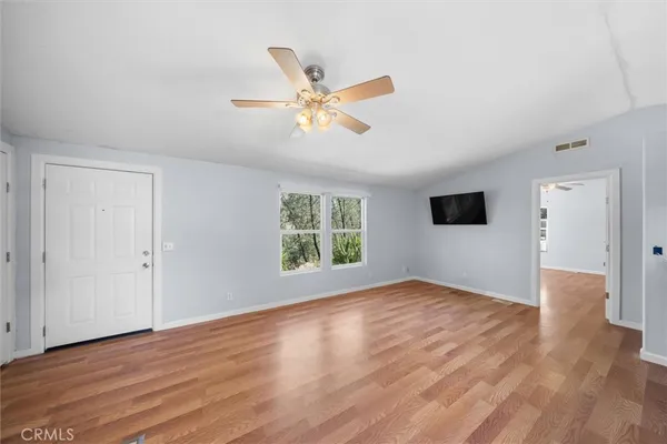 a view of an empty room with wooden floor and a window