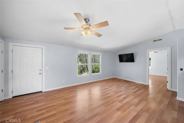 a view of an empty room with wooden floor and a window