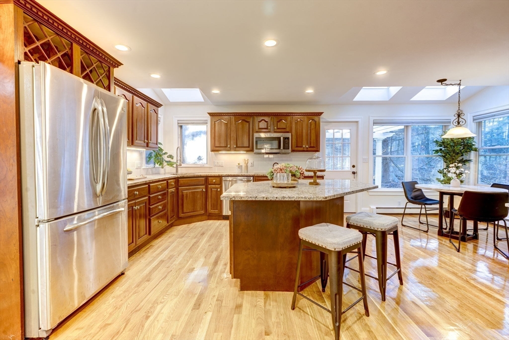 17 Bridle Path Walpole, MA 02081 - Photo 12 of 38 a kitchen with stainless steel appliances granite countertop a refrigerator a sink a stove a dining table and chairs with wooden floor