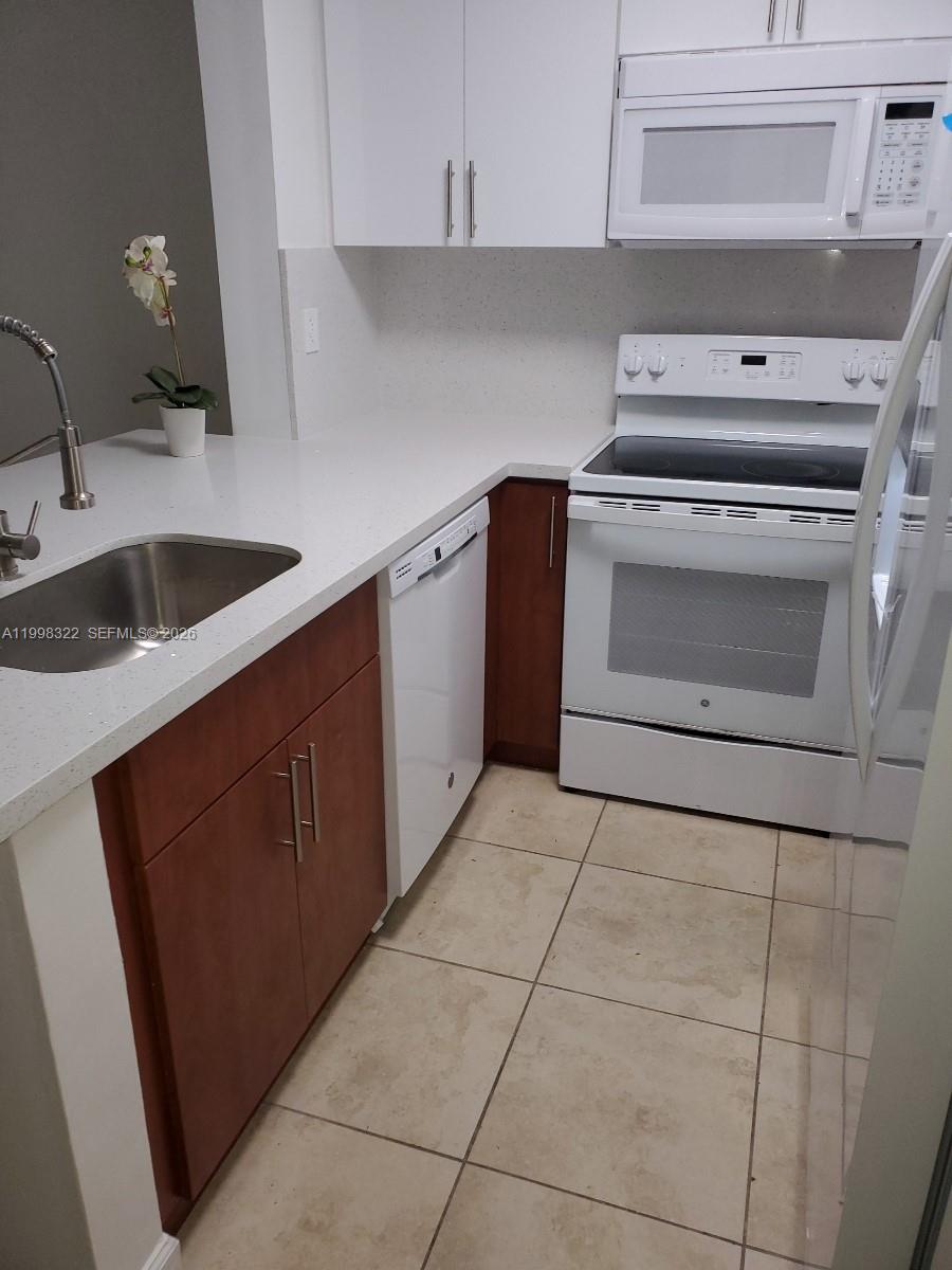 15241 Southwest 80th Street, Unit 307 Miami, FL 33193 - Photo 2 of 13 a kitchen with a stove top oven and cabinets