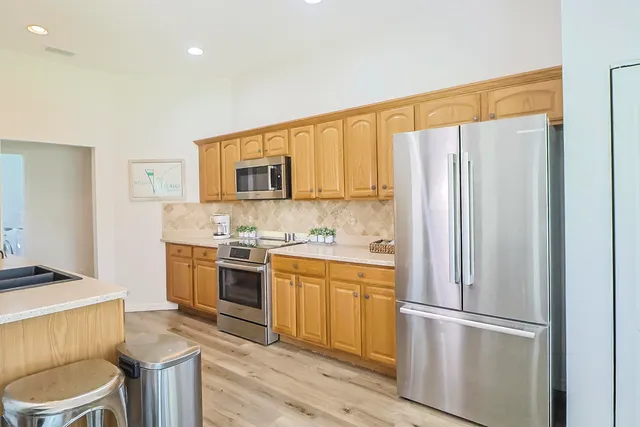 a kitchen with stainless steel appliances granite countertop wooden cabinets a stove a sink and dishwasher with wooden floor