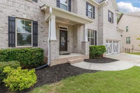 a view of a brick house with many windows plants and large tree