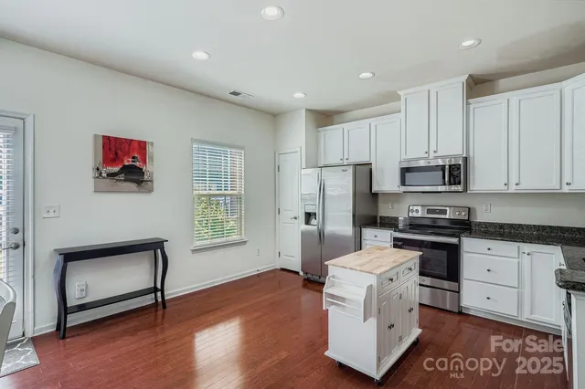 a kitchen with stainless steel appliances granite countertop a stove a sink dishwasher a refrigerator and a microwave oven with wooden floor