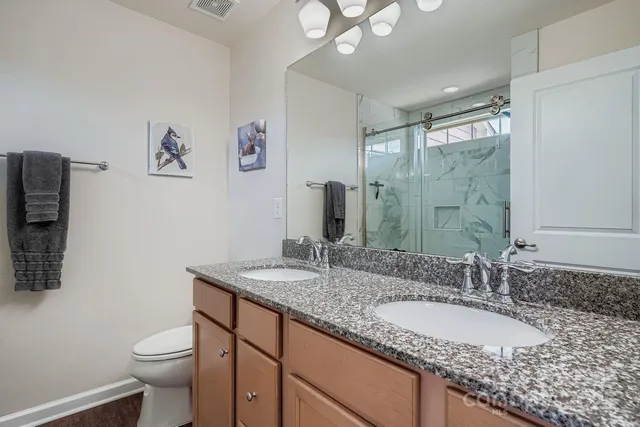 a bathroom with a granite countertop double vanity sink and a mirror