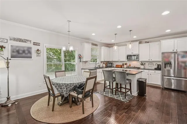 a kitchen with stainless steel appliances granite countertop a dining table chairs refrigerator sink and cabinets