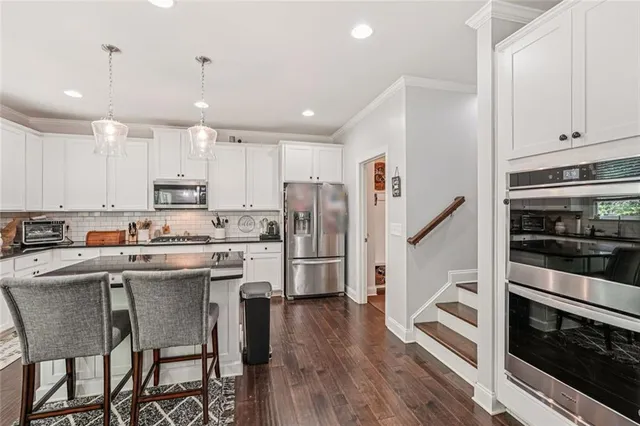 a kitchen with kitchen island white cabinets and stainless steel appliances