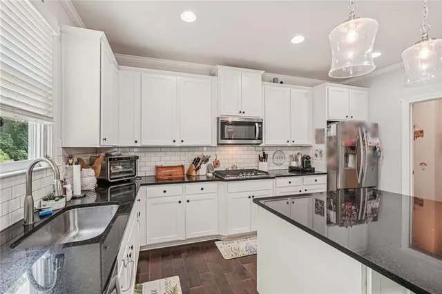 a kitchen with stainless steel appliances granite countertop a sink a stove and cabinets