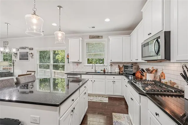 a kitchen with kitchen island granite countertop a sink a counter space appliances and cabinets