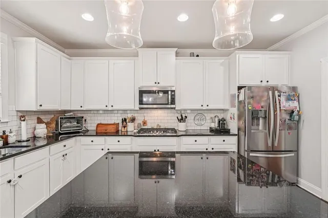 a kitchen with granite countertop a refrigerator sink and cabinets