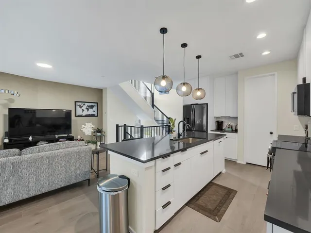 a kitchen with granite countertop a sink a microwave oven a stove and a refrigerator with wooden floor