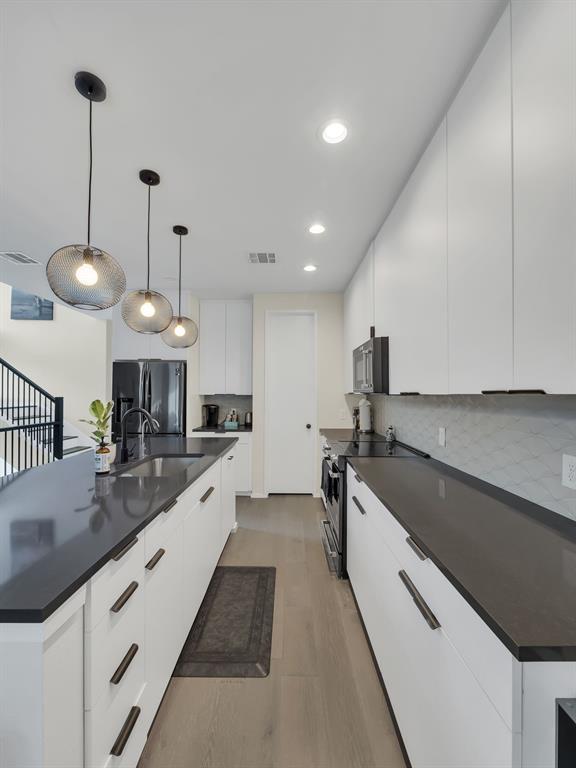 4703 Munger Avenue, Unit 101 Dallas, TX 75204 - Photo 3 of 26 a large kitchen with stainless steel appliances kitchen island a large counter space a sink and a wooden floor