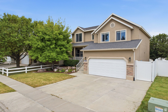 2223 North Pointe Meadow Loop Lehi, UT 84048 - Photo 2 of 56 Two-story residence featuring a two-car garage with stone accents, a concrete driveway, and mature trees