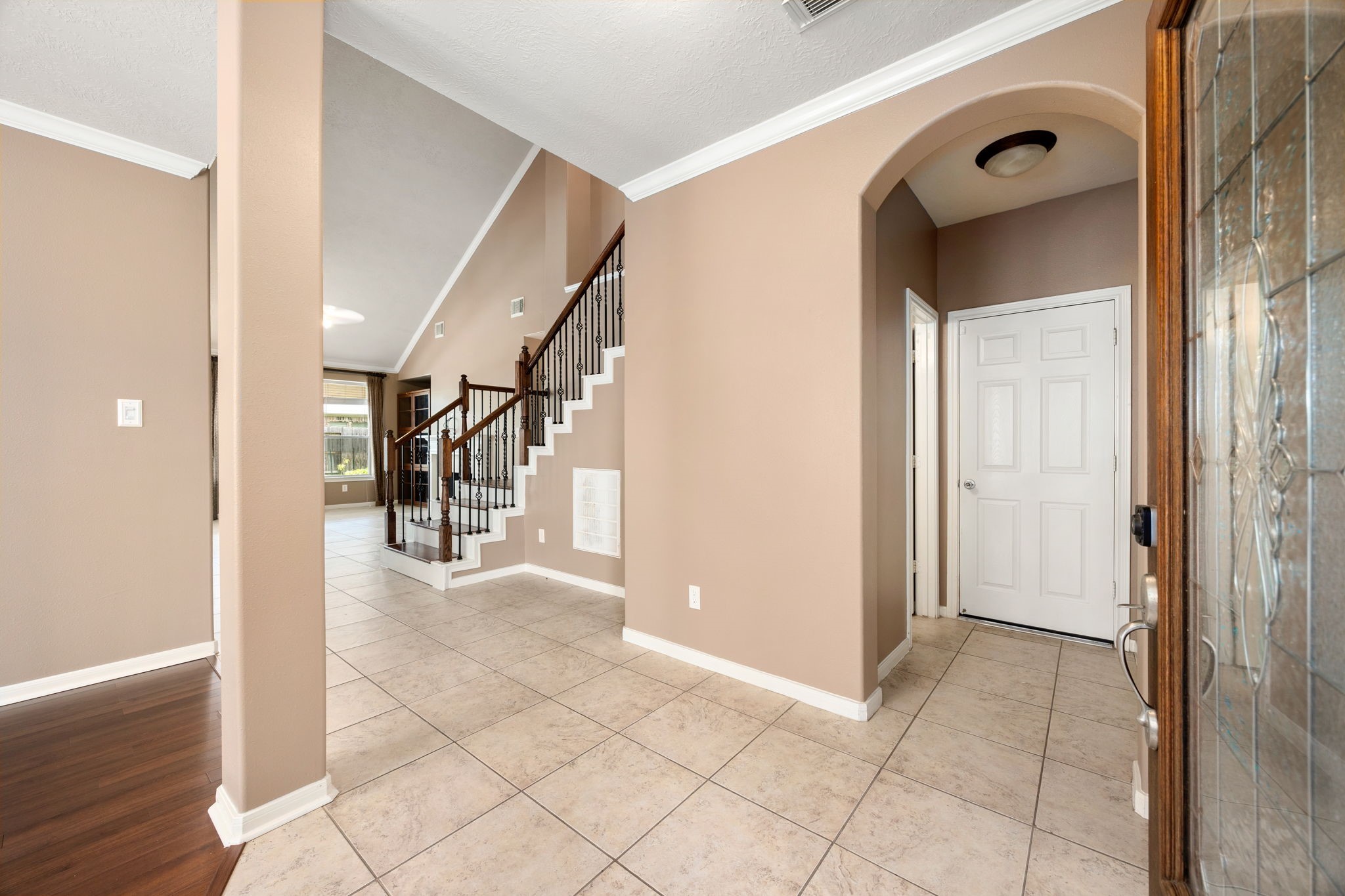 4526 Countrypines Drive Spring, TX 77388 - Photo 7 of 38 Step inside a grand, welcoming foyer featuring tile flooring, elegant crown molding, and an architectural arched entryway. The spacious entry opens seamlessly to the main living areas and a striking staircase with wrought-iron spindles.