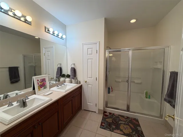a spacious bathroom with a double vanity sink a mirror and shower