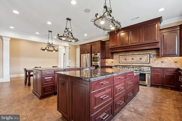 a kitchen with stainless steel appliances kitchen island granite countertop a table chairs sink and cabinets