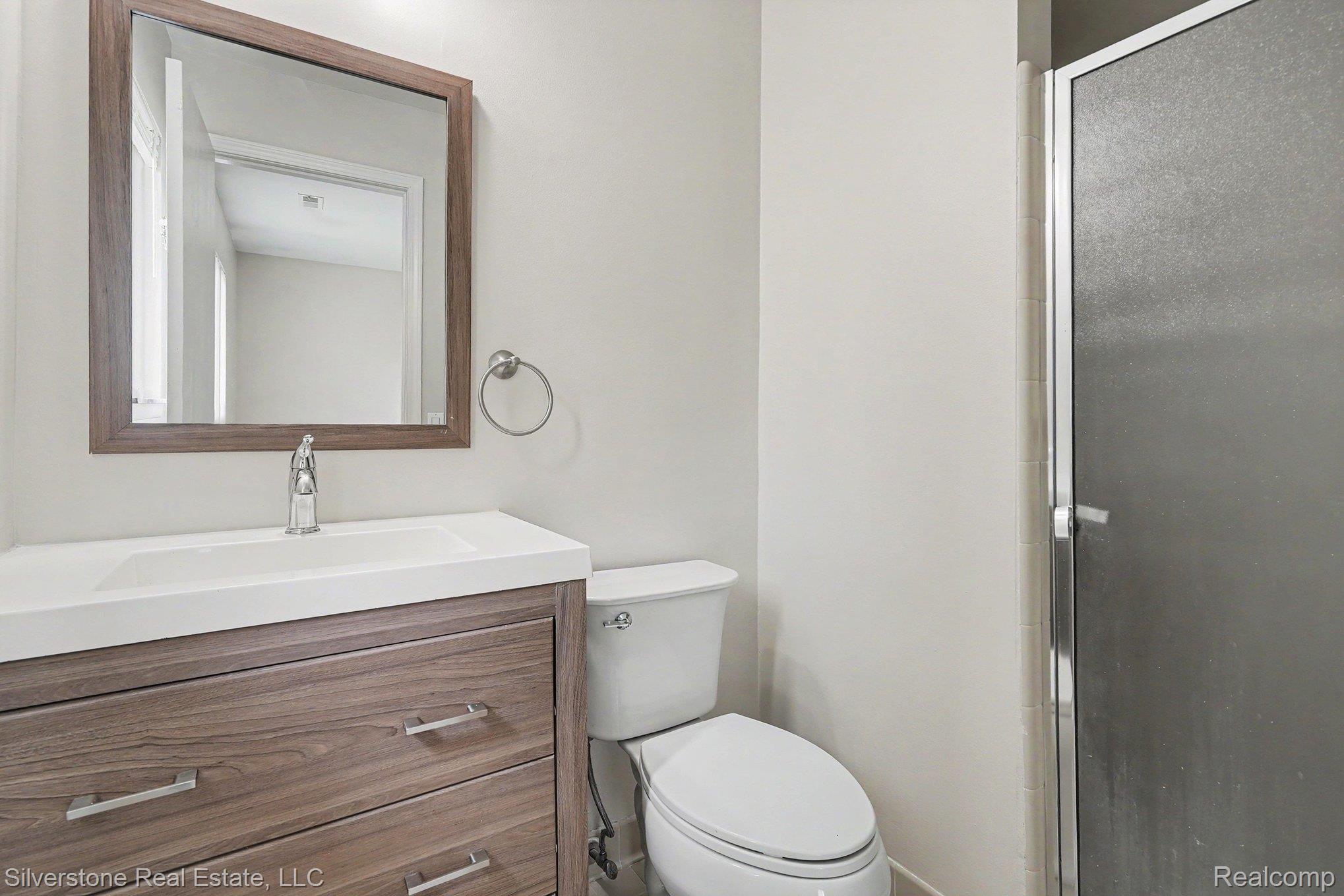 1502 Meadowside Drive Rochester, MI 48307 - Photo 20 of 27 Bathroom featuring a wood-finish vanity with an integrated white sink, chrome faucet, and contemporary framed mirror