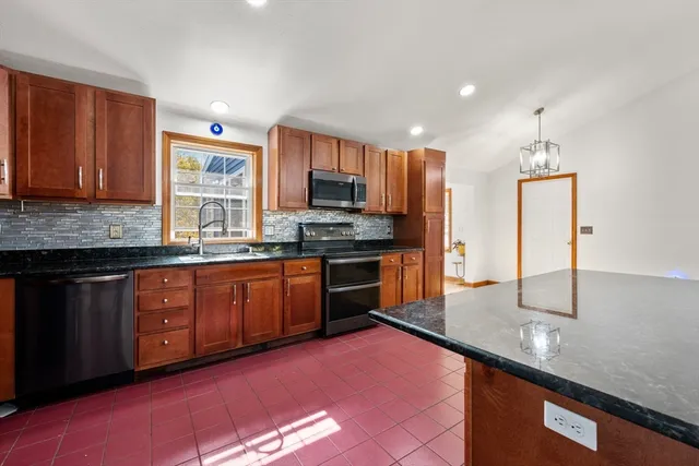 a kitchen with stainless steel appliances granite countertop a sink a stove and a refrigerator