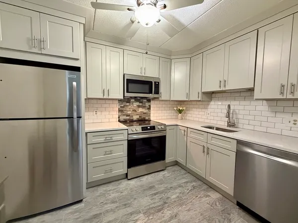 a kitchen with stainless steel appliances granite countertop a refrigerator a stove a sink and a microwave