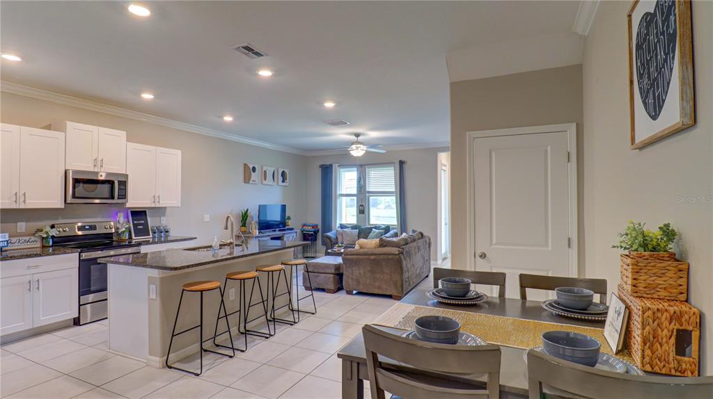 31632 Blue Passing Loop Wesley Chapel, FL 33545 - Photo 6 of 48 a kitchen with a stove a sink a dining table and chairs