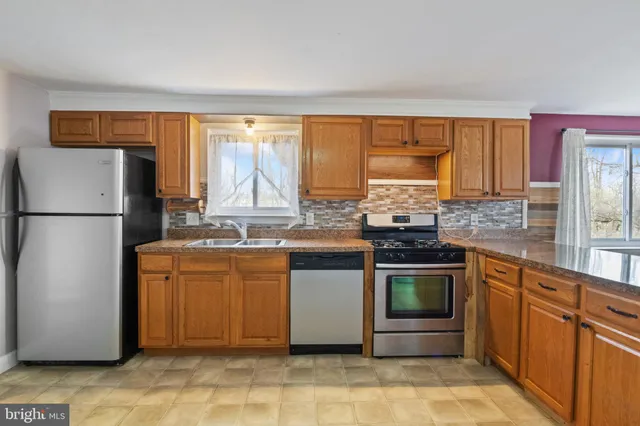 a kitchen with stainless steel appliances granite countertop a refrigerator a sink dishwasher a stove with wooden cabinets