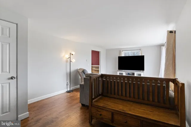 a living room with furniture a flat screen tv and a refrigerator