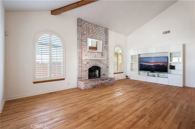 a view of empty room with fireplace and wooden floor
