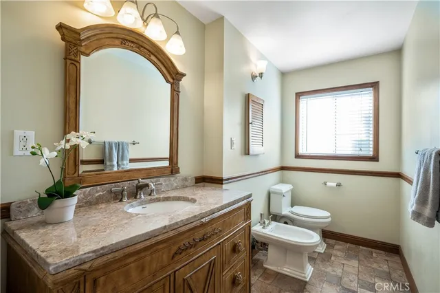 a bathroom with a granite countertop toilet a sink and a mirror