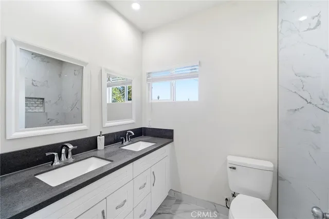 a bathroom with a granite countertop sink mirror and a toilet