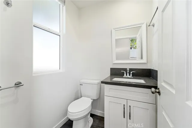 a bathroom with a granite countertop sink toilet and mirror