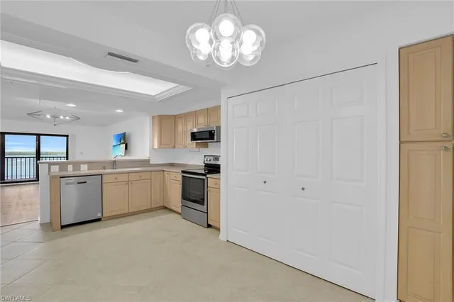 a open kitchen with a refrigerator a stove top oven a sink dishwasher and white cabinets with wooden floor