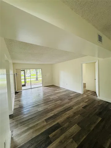 a view of empty room with wooden floor and window