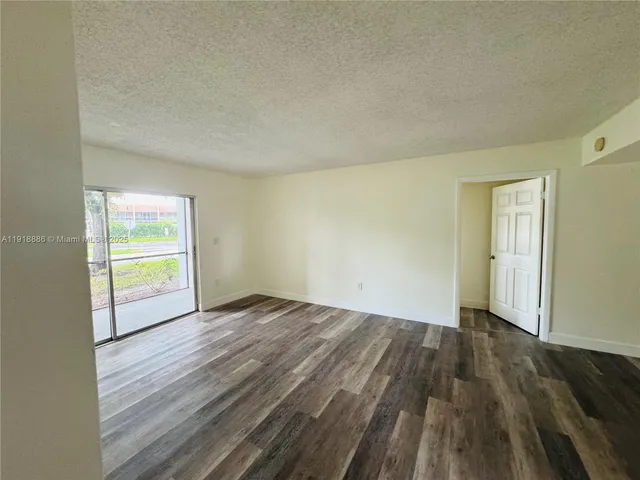 a view of an empty room and wooden floor and a window